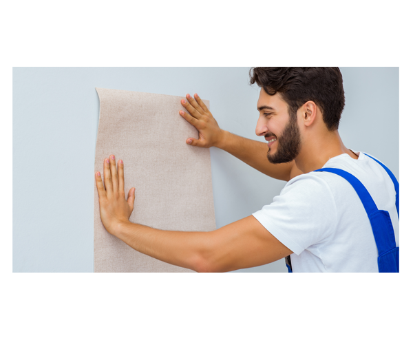 A man holding a piece of wallpaper against a wall.